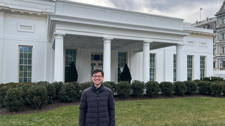 Photograph of USDS intern Sam Feudo standing in front of the West Wing of the White House.